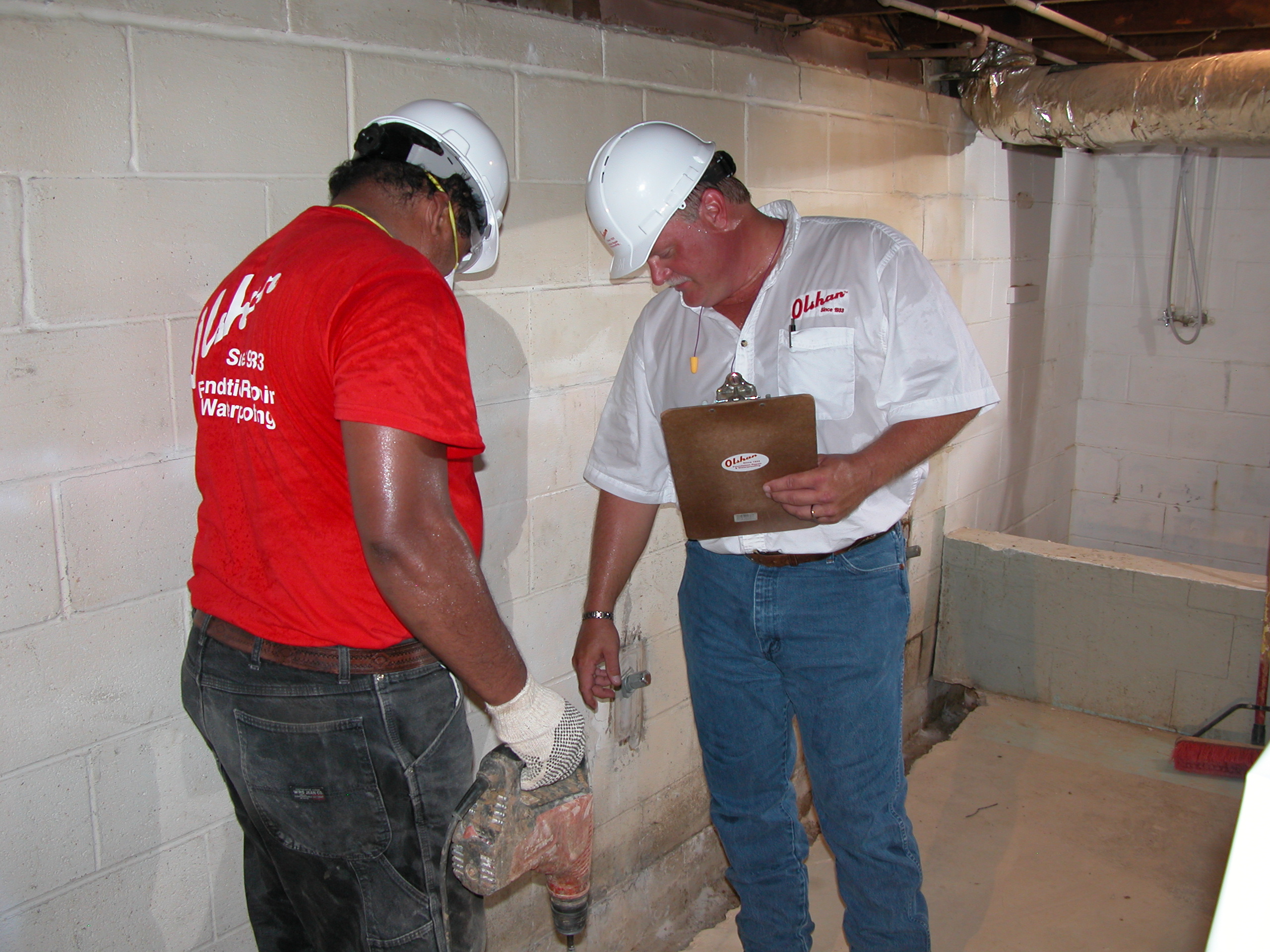 Basement waterproofing specialists assessing wall conditions with professional equipment to plan effective residential water damage prevention. Basement waterproofing specialists assessing wall conditions with professional equipment to plan effective residential water damage prevention.