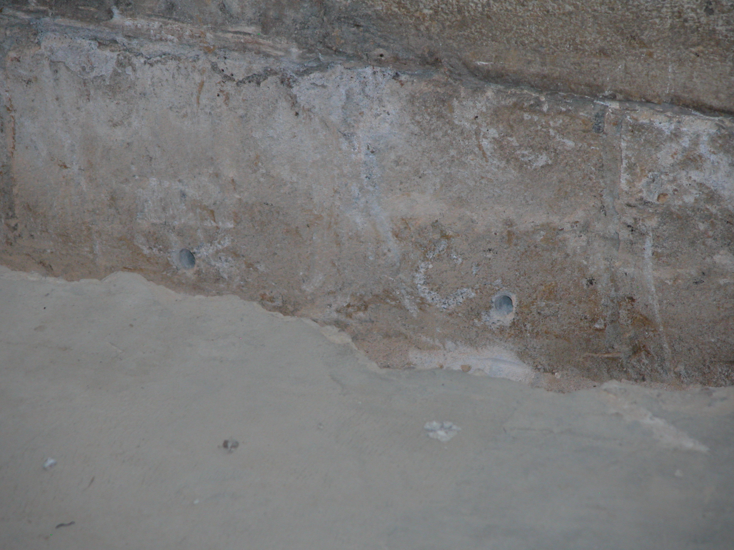 Advanced sealing technique applied to basement wall to prevent water seepage and structural issues Drilled holes in basement floor to better direct water along the carved channel.