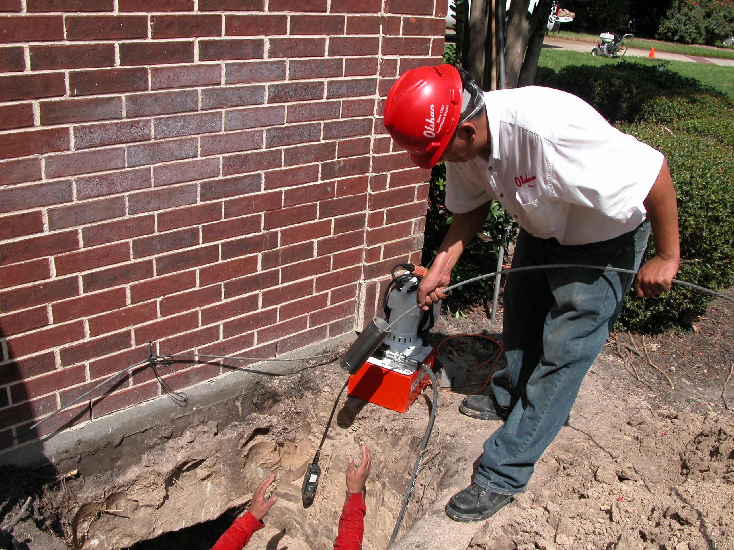 Identifying Two Certified Structural Technicians installing the CableLock system underneath a home.